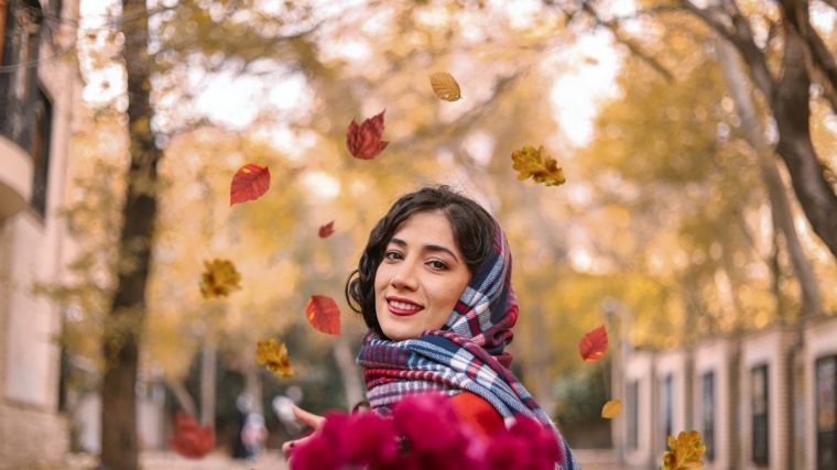 girl in red and white plaid scarf standing under red flowers